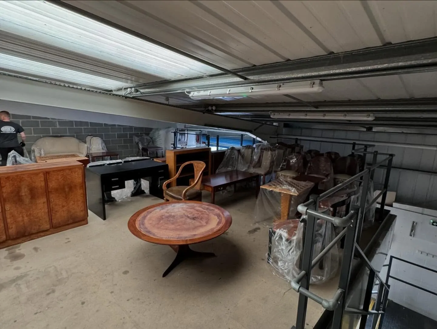 Antique chairs, tables and cabinets arranged on a warehouse mezzanine after a dealer stock relocation