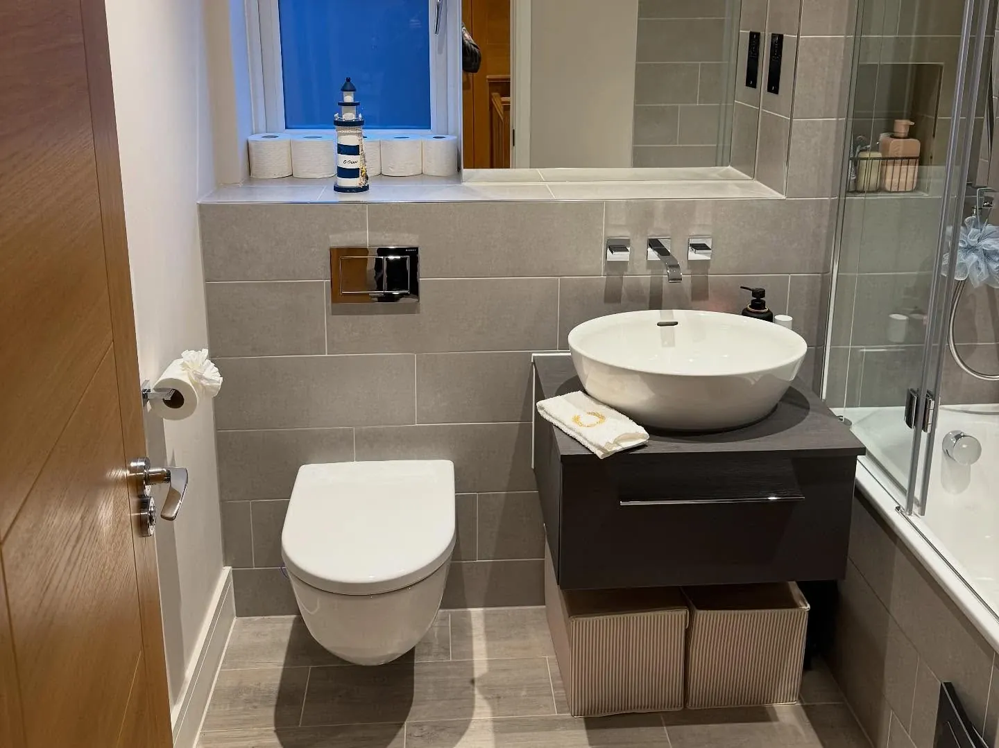 A bathroom set up after a move with towels folded, toiletries placed and toilet rolls stacked on the windowsill