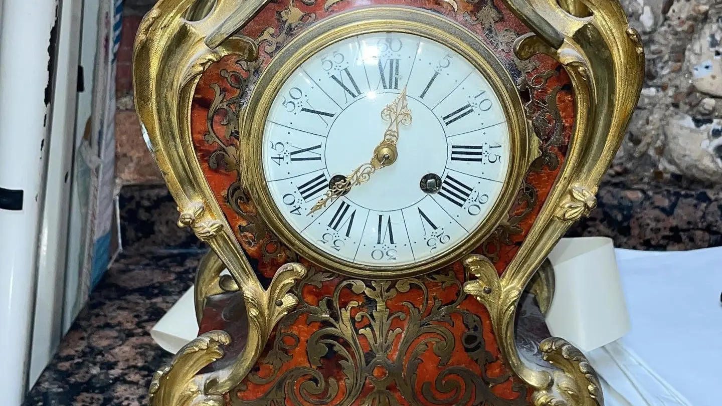 Close-up of the white enamel dial and gilt mounts of a boulle bracket clock
