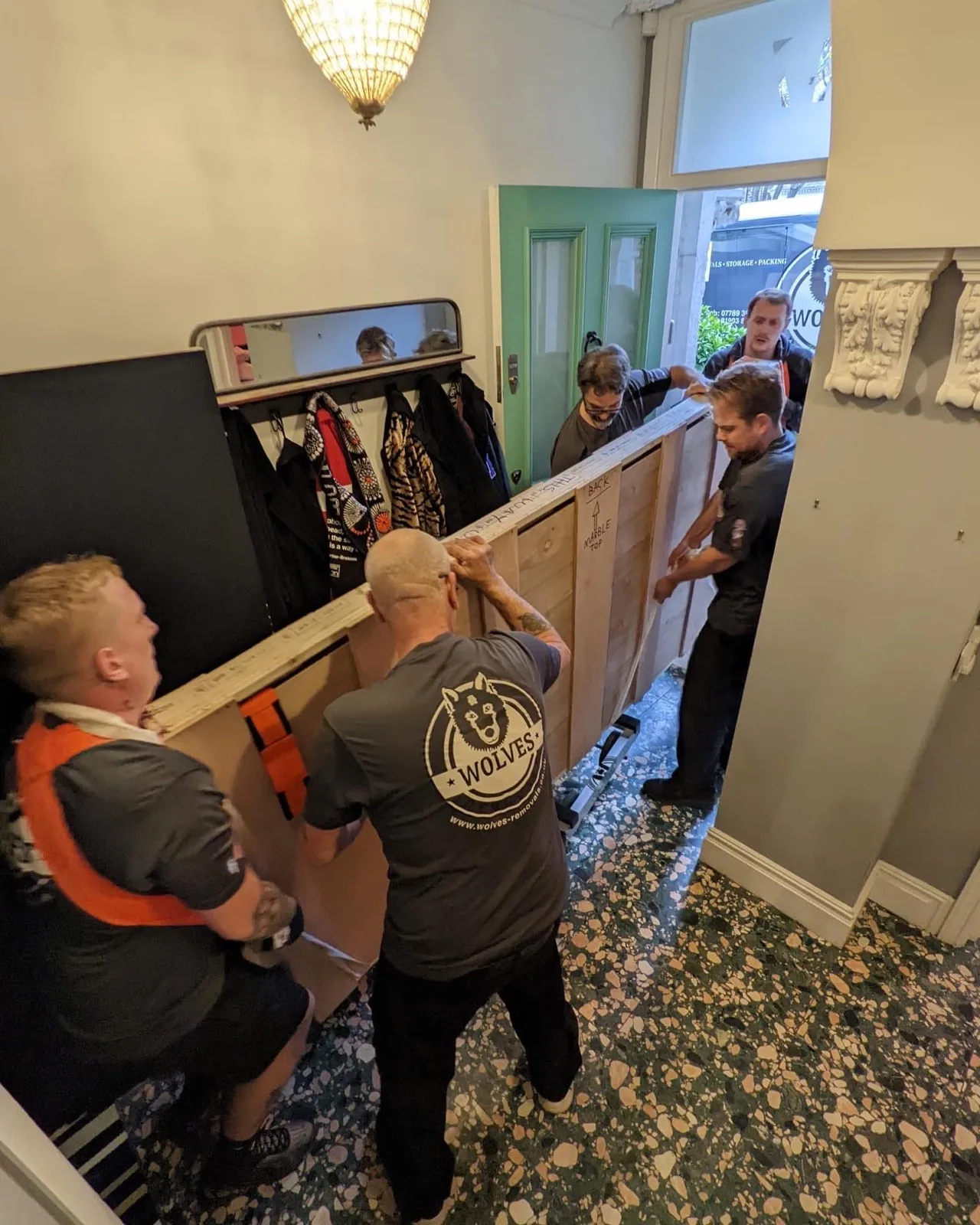 Carrying wardrobe into house hallway