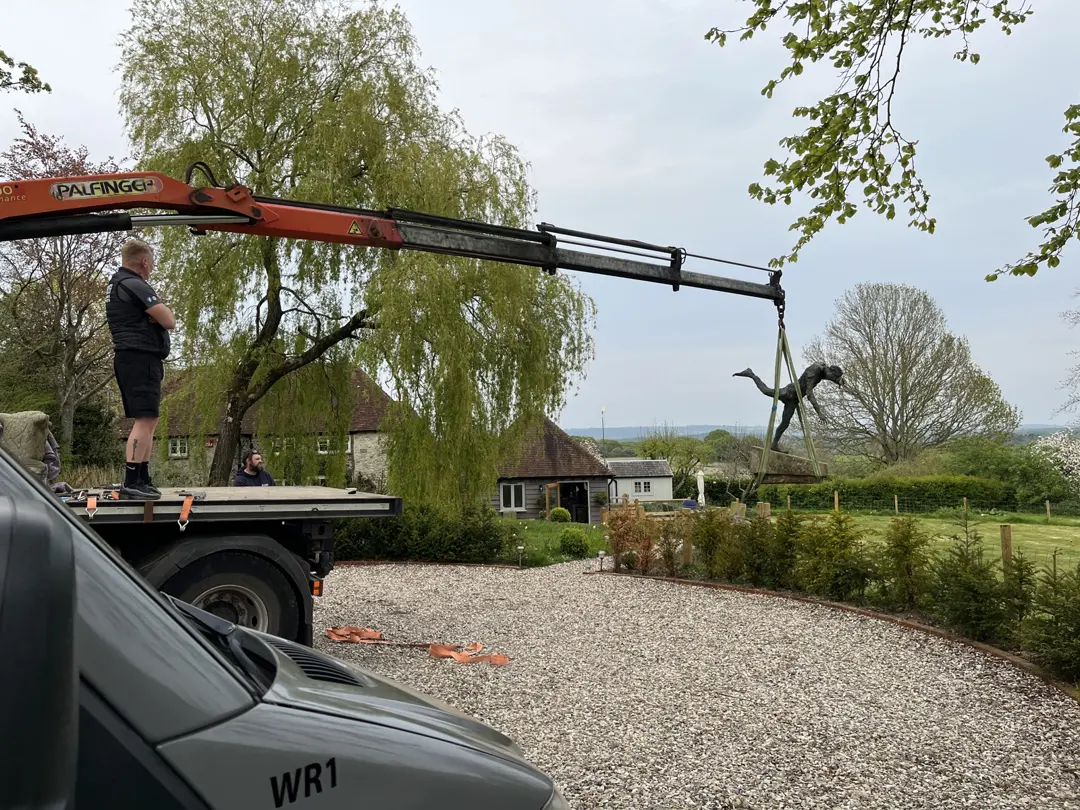 Crane loading a statue onto a trailer