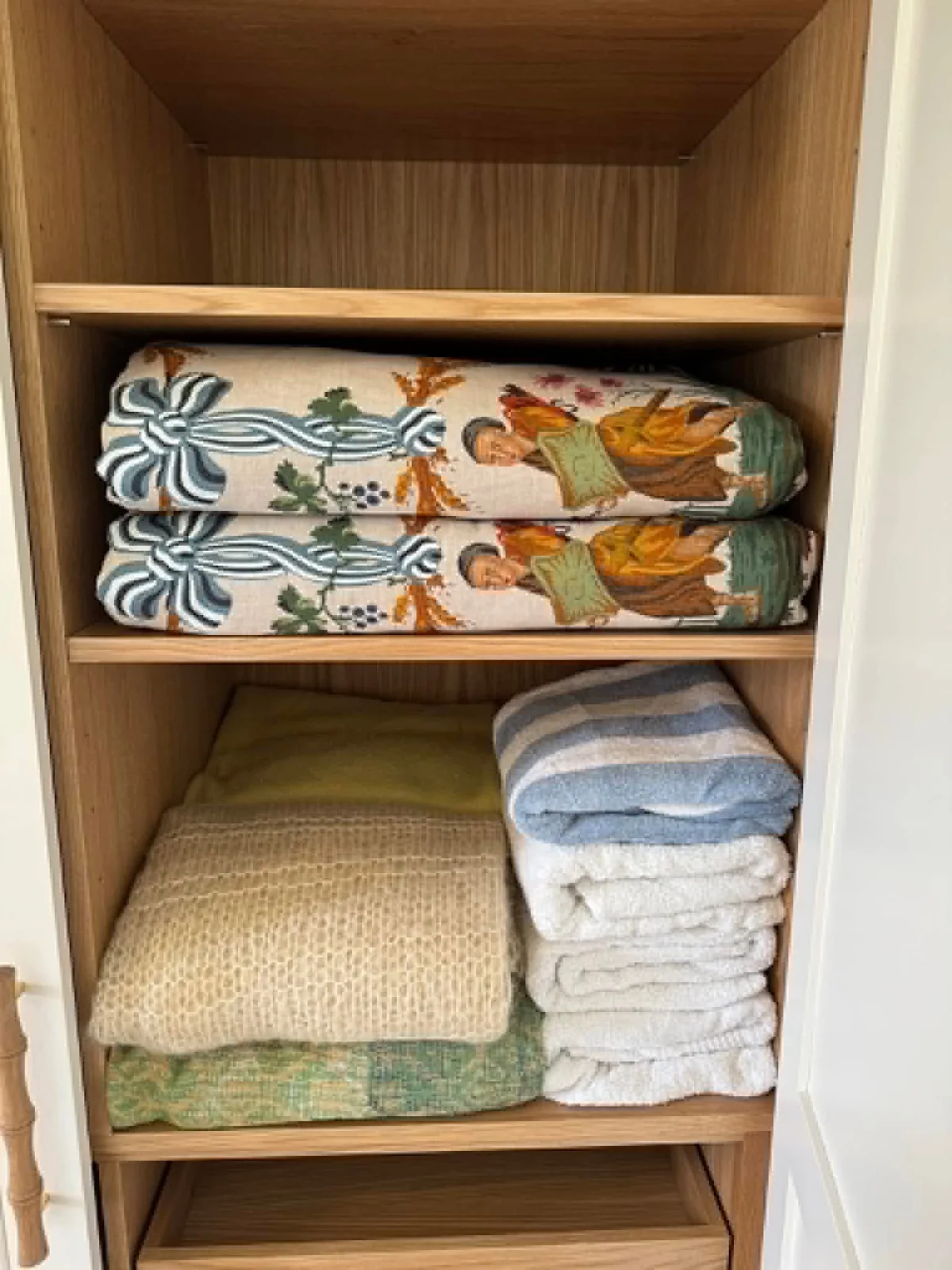 Blankets and towels folded and arranged in a wooden wardrobe during a full unpacking service