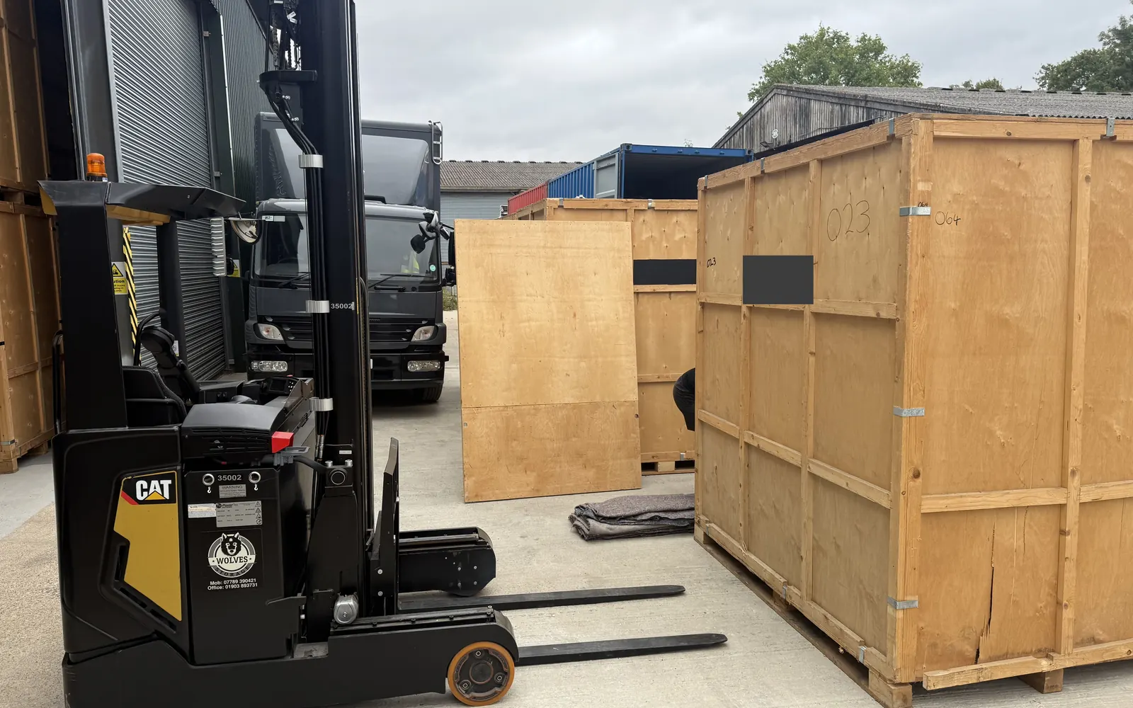 A Wolves Removals forklift positioning a timber storage container in the warehouse yard