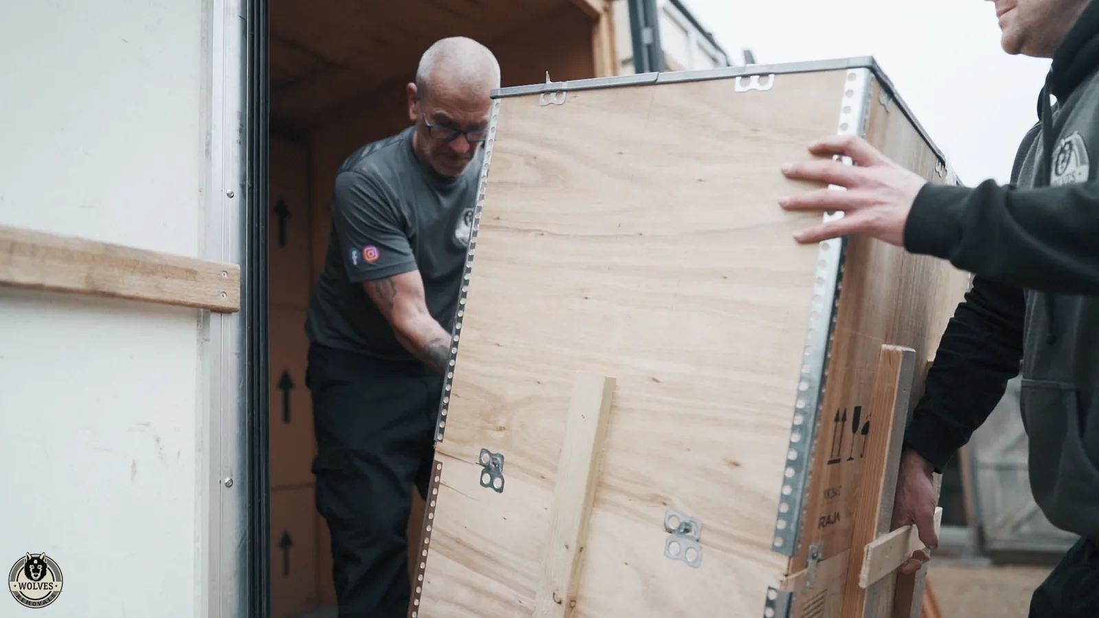 A Wolves Removals crew loading a wooden crate into a storage container