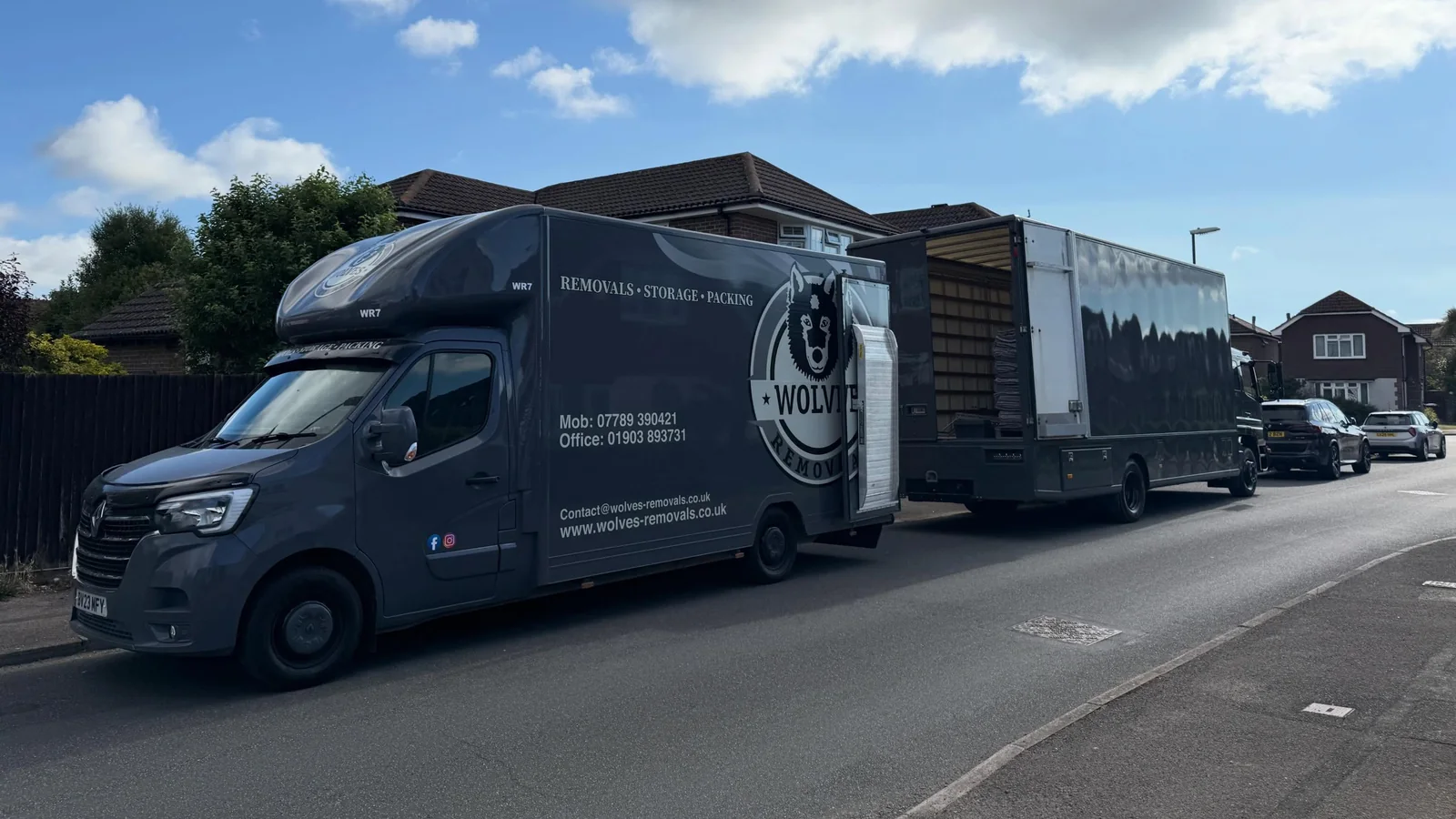 Two branded Wolves Removals lorries loading on a residential street during a one-day house move