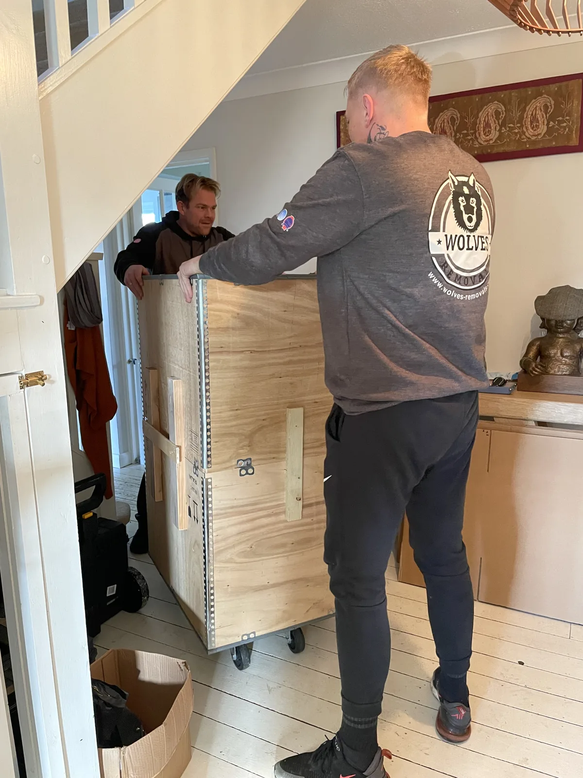 Crew packing items into a wooden crate in a hallway