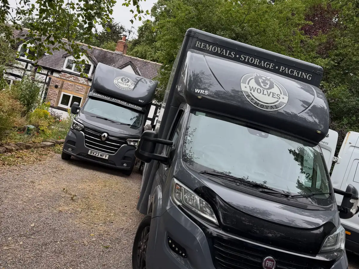 Two Wolves Removals lorries on the gravel drive of a brick and timber cottage in Cheshire