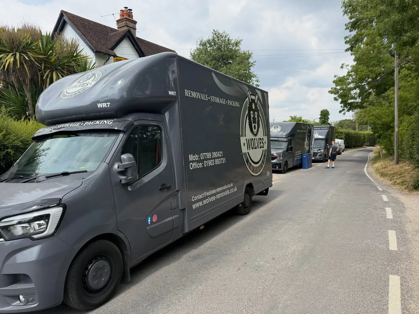 Three Wolves Removals lorries parked nose to tail on a narrow Sussex lane during loading