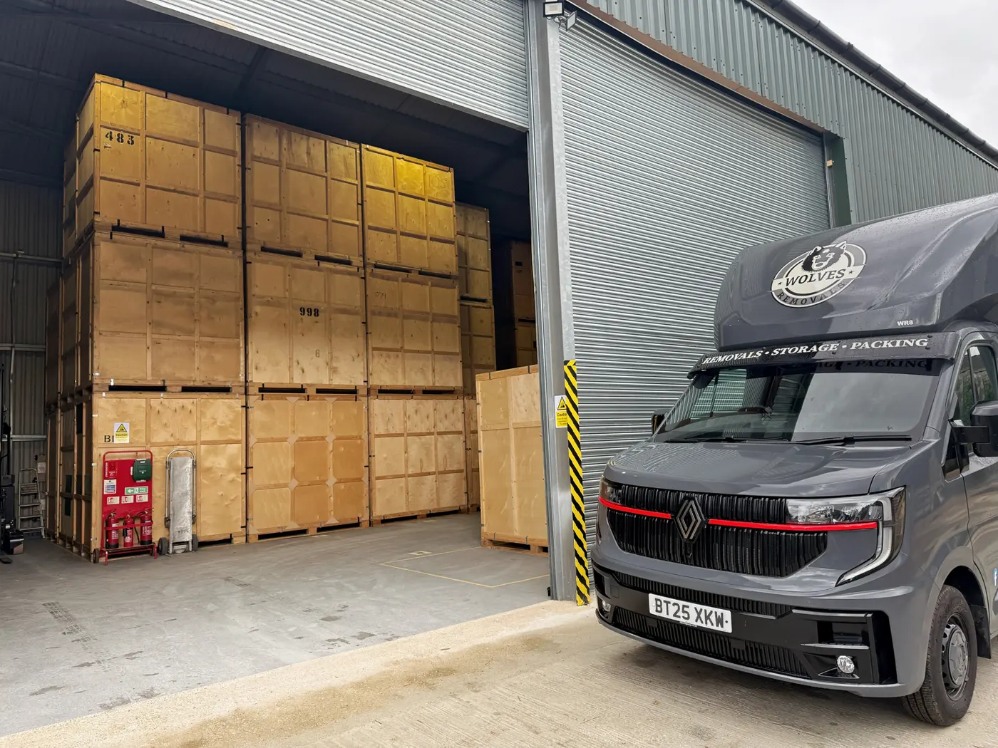 Wolves Removals van beside stacked crates at the depot