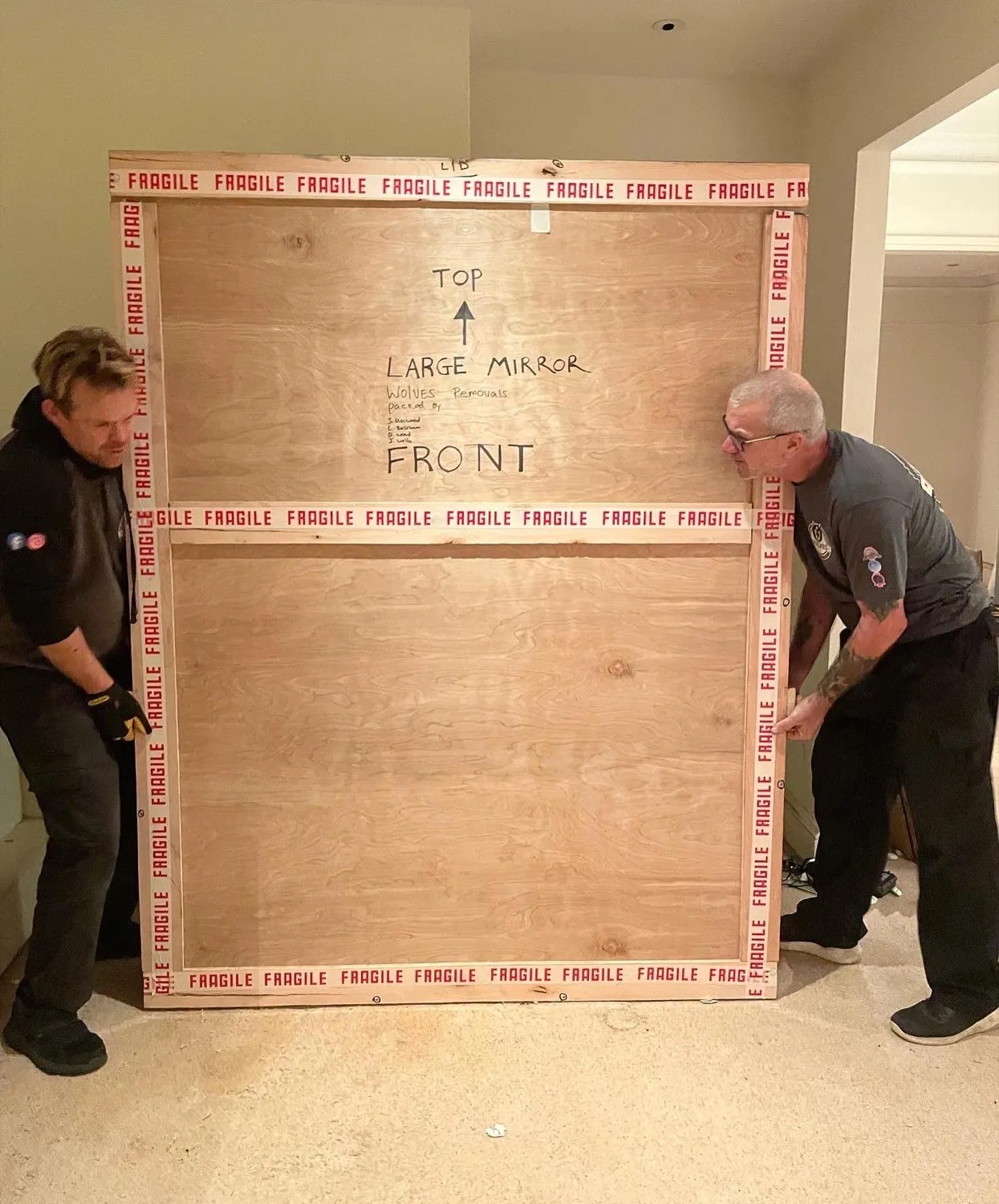 Two movers positioning a bespoke timber crate in Surrey