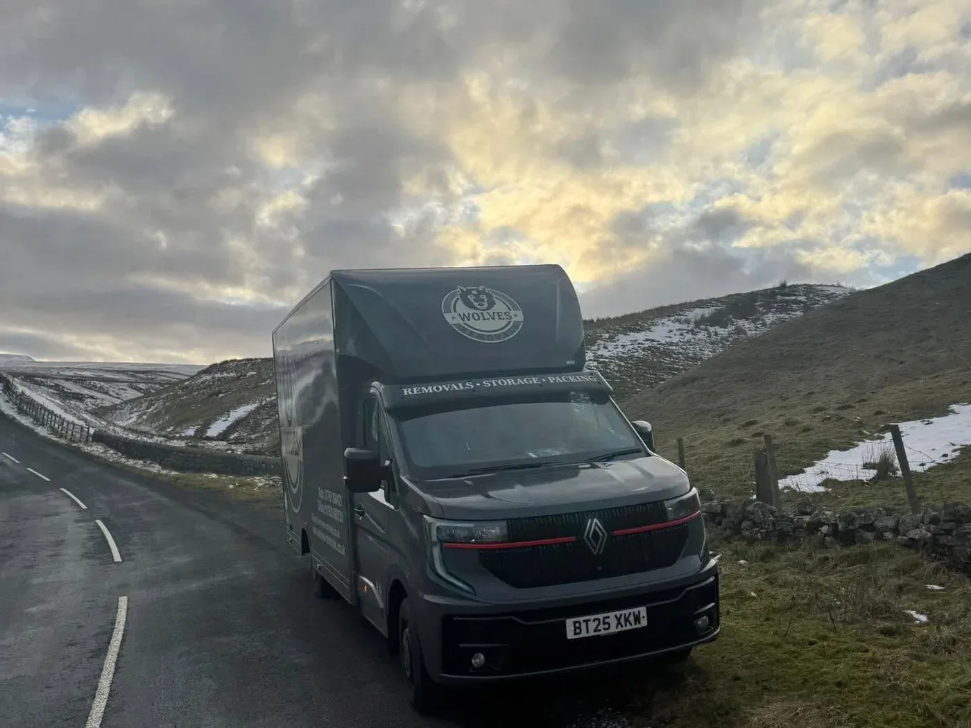 A Wolves Removals lorry on a snow-lined moorland road in the North Pennines