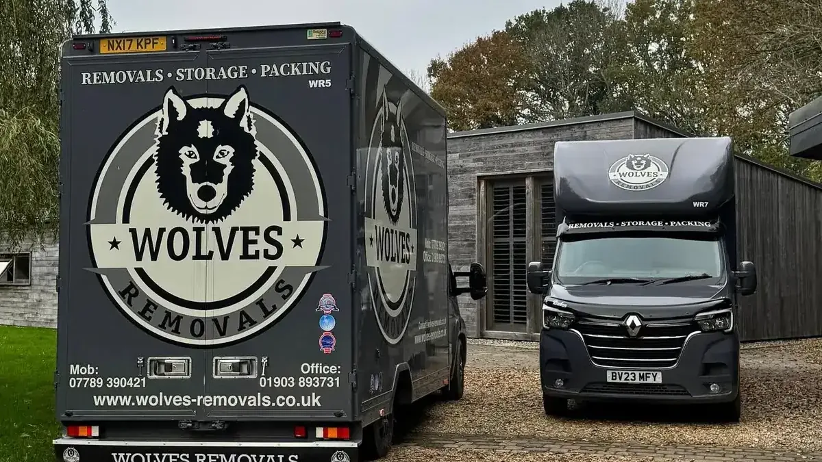 A Wolves Removals lorry and Luton van on the drive of a timber-clad house on the edge of Horsham…