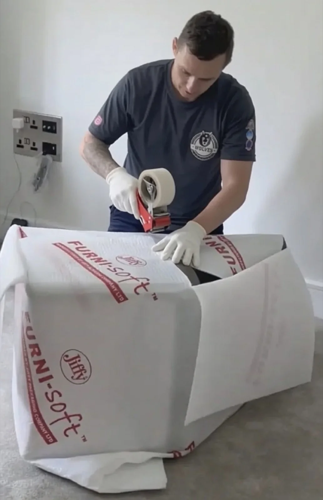 A Wolves Removals mover in white gloves taping Furni-Soft padding around furniture