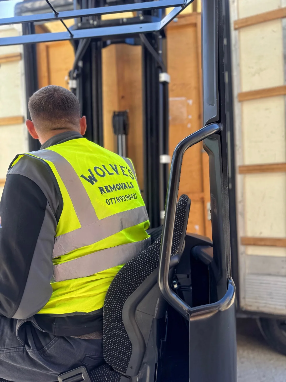 A Wolves Removals operator driving a forklift to load wooden storage containers