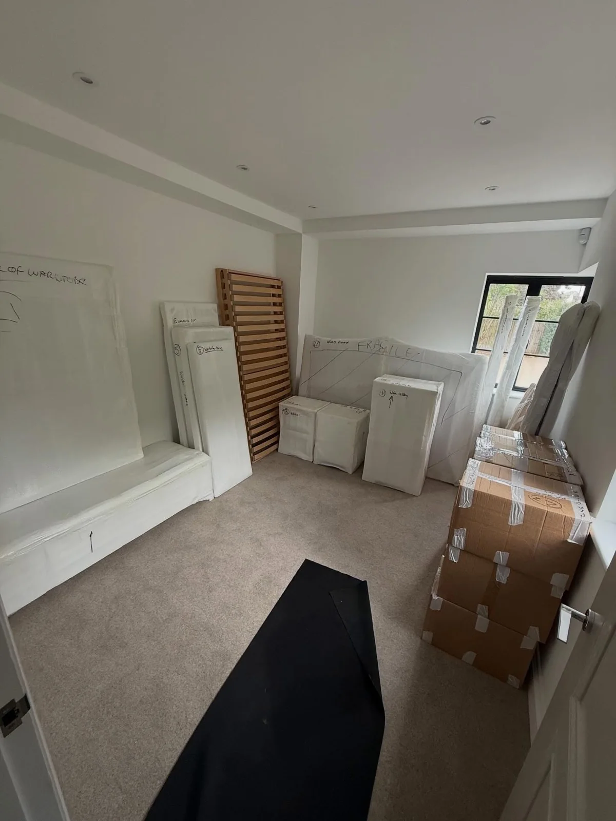 A room of wrapped furniture and labelled boxes packed ready for delivery