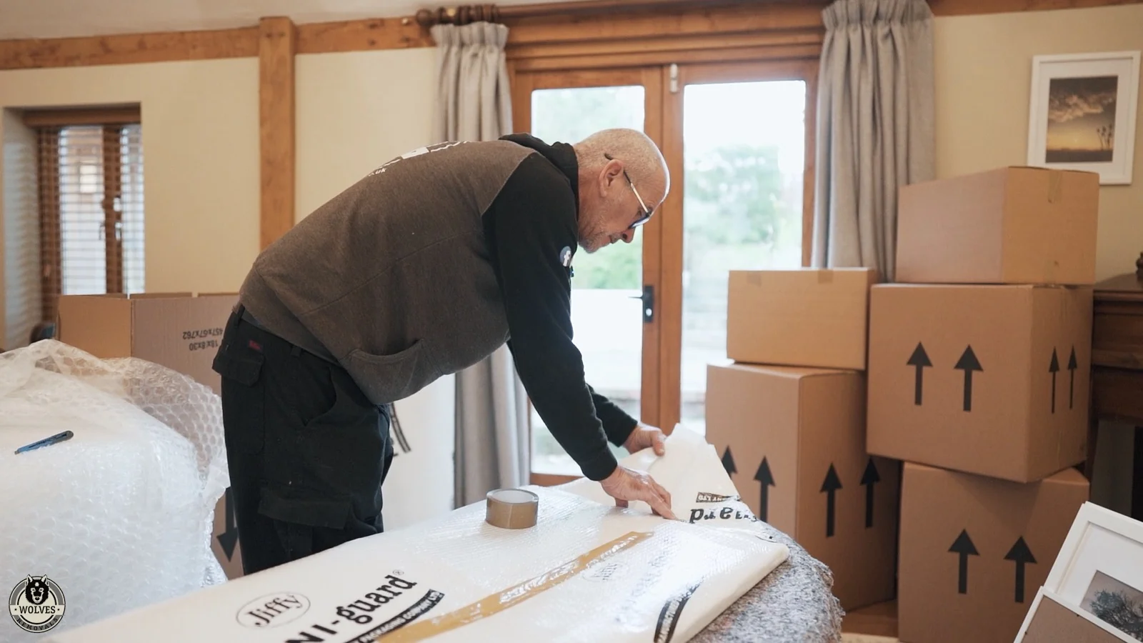 A Wolves Removals packer wrapping a framed picture for export with shipping boxes